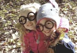 Two children wearing large round glasses and smiling