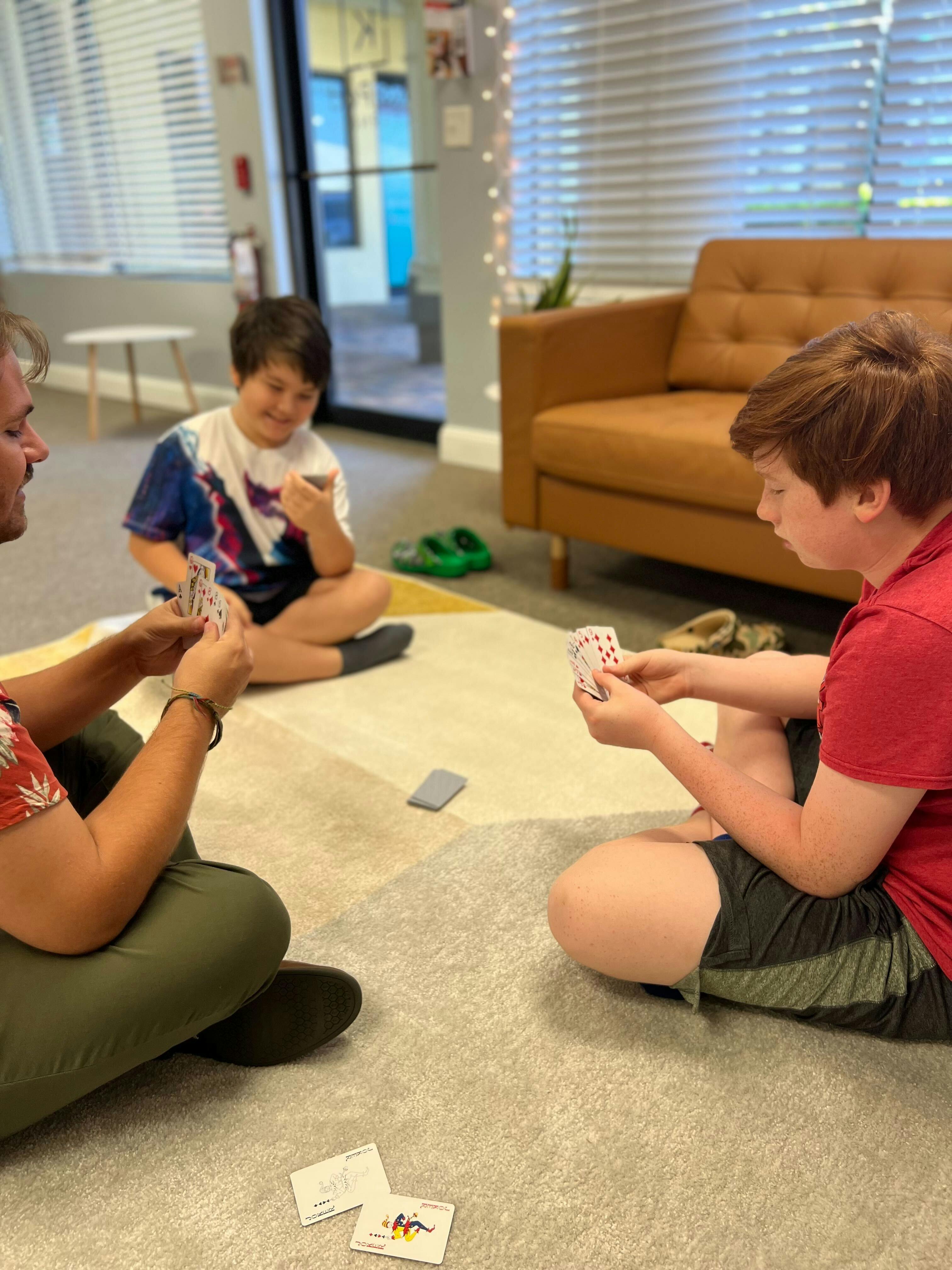 Three people sitting on the floor playing cards