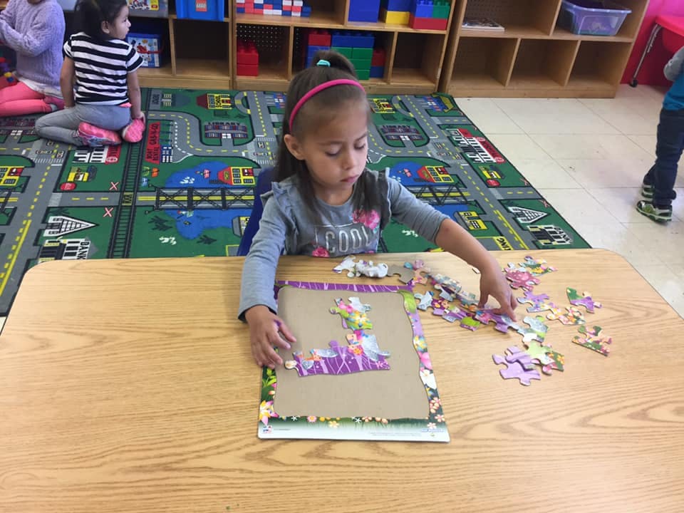 Child assembling a puzzle at a table