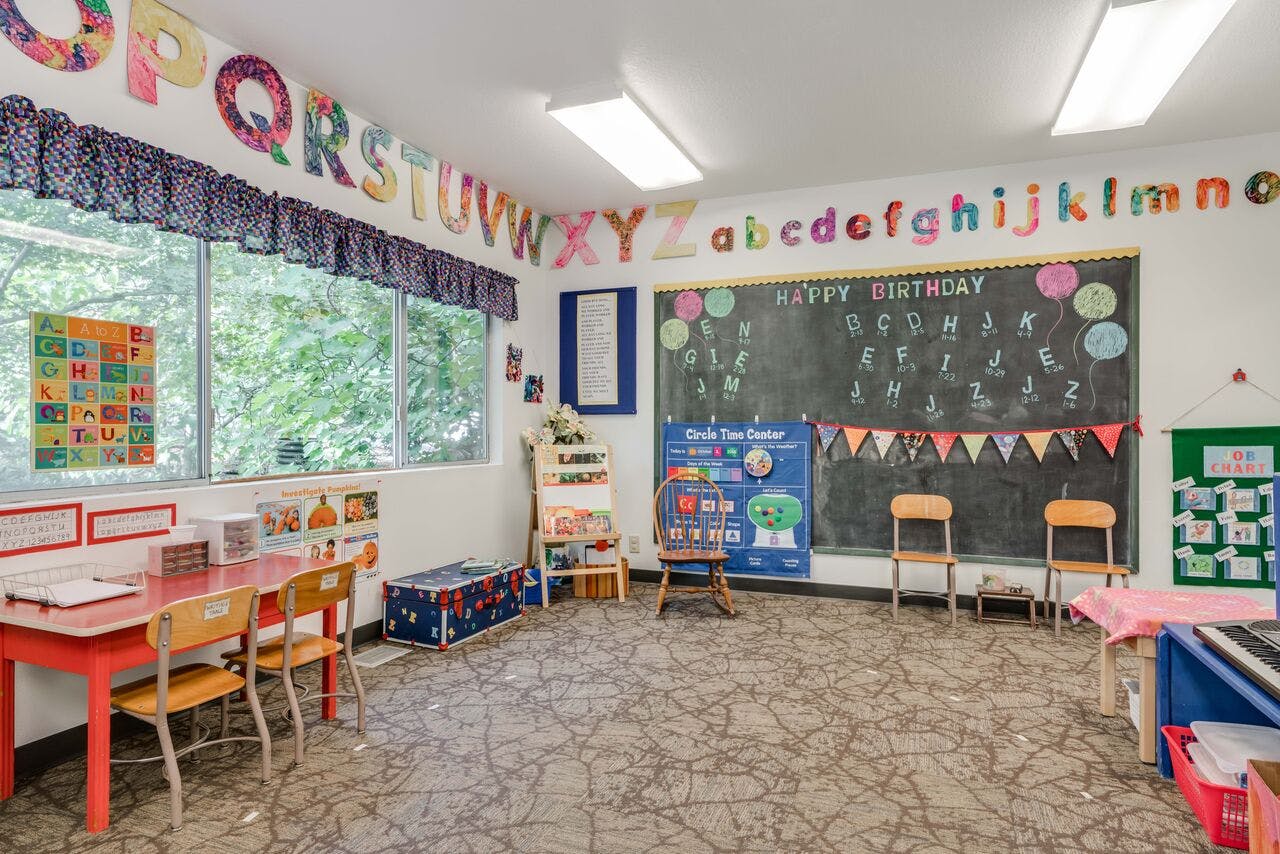 Classroom with a chalkboard, small tables and chairs, and alphabet decorations