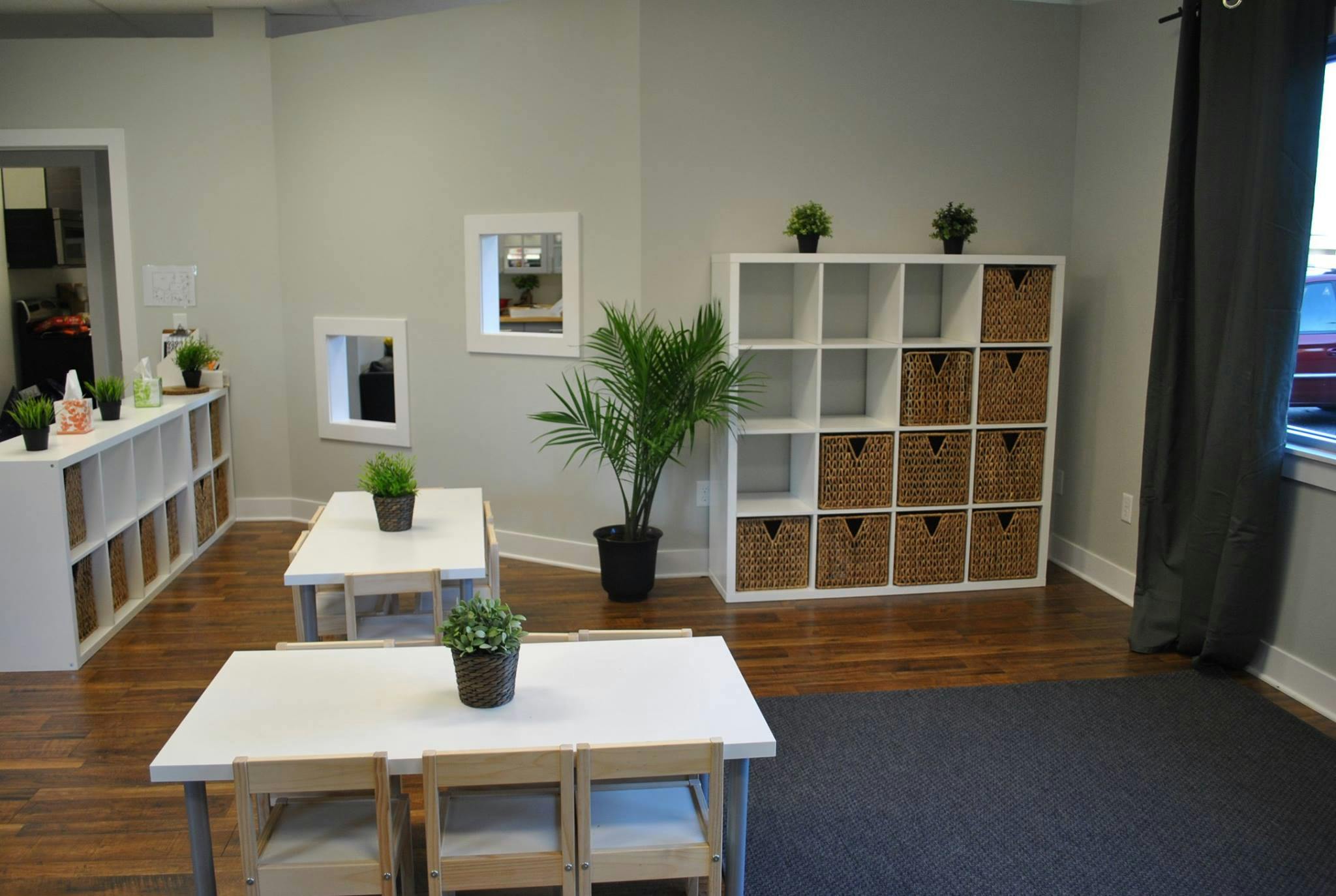 Classroom with small tables and chairs, storage shelves, and plants
