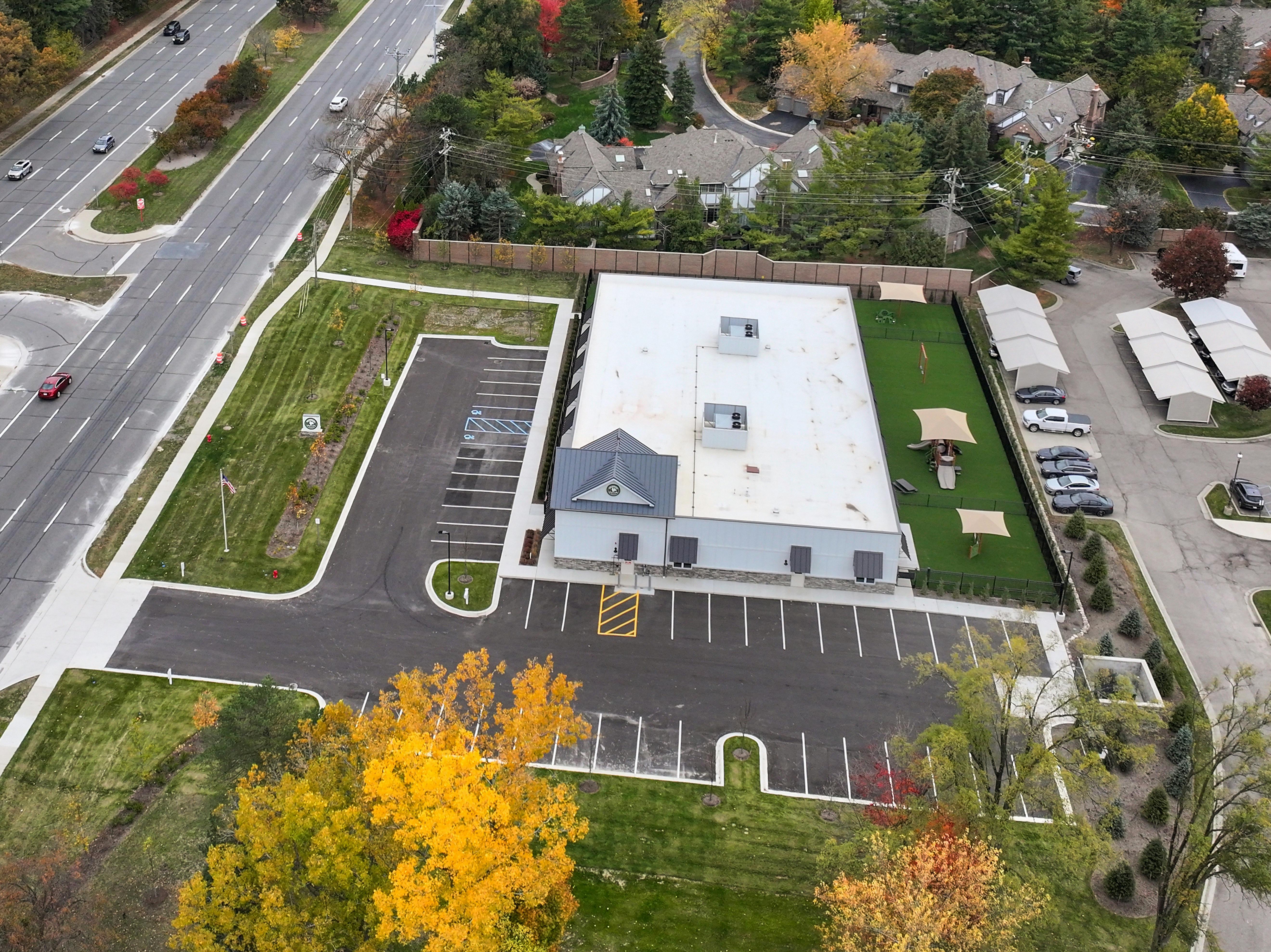 Aerial view of a building with a parking lot and a playground next to a road