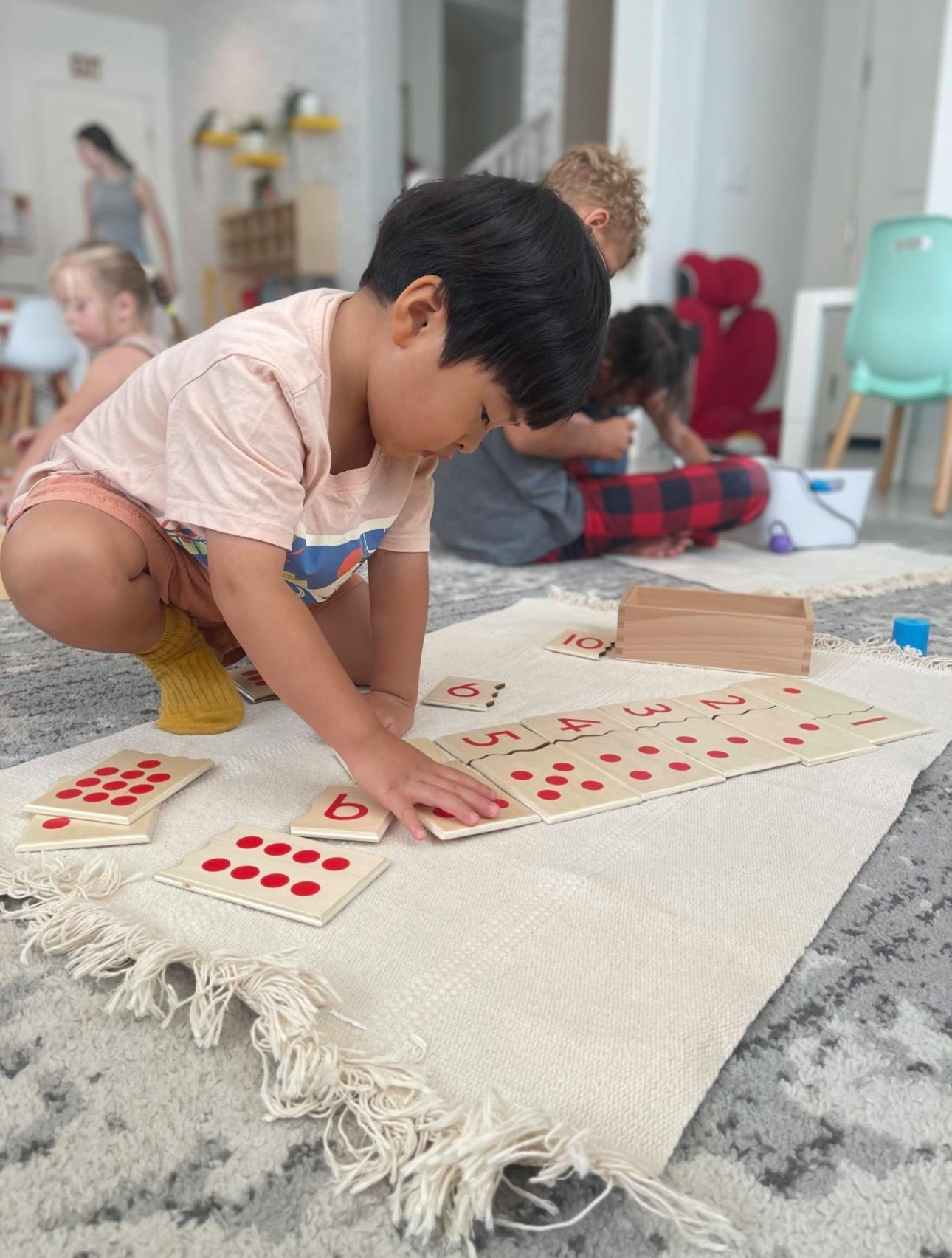 Child matching number tiles on a rug in a classroom