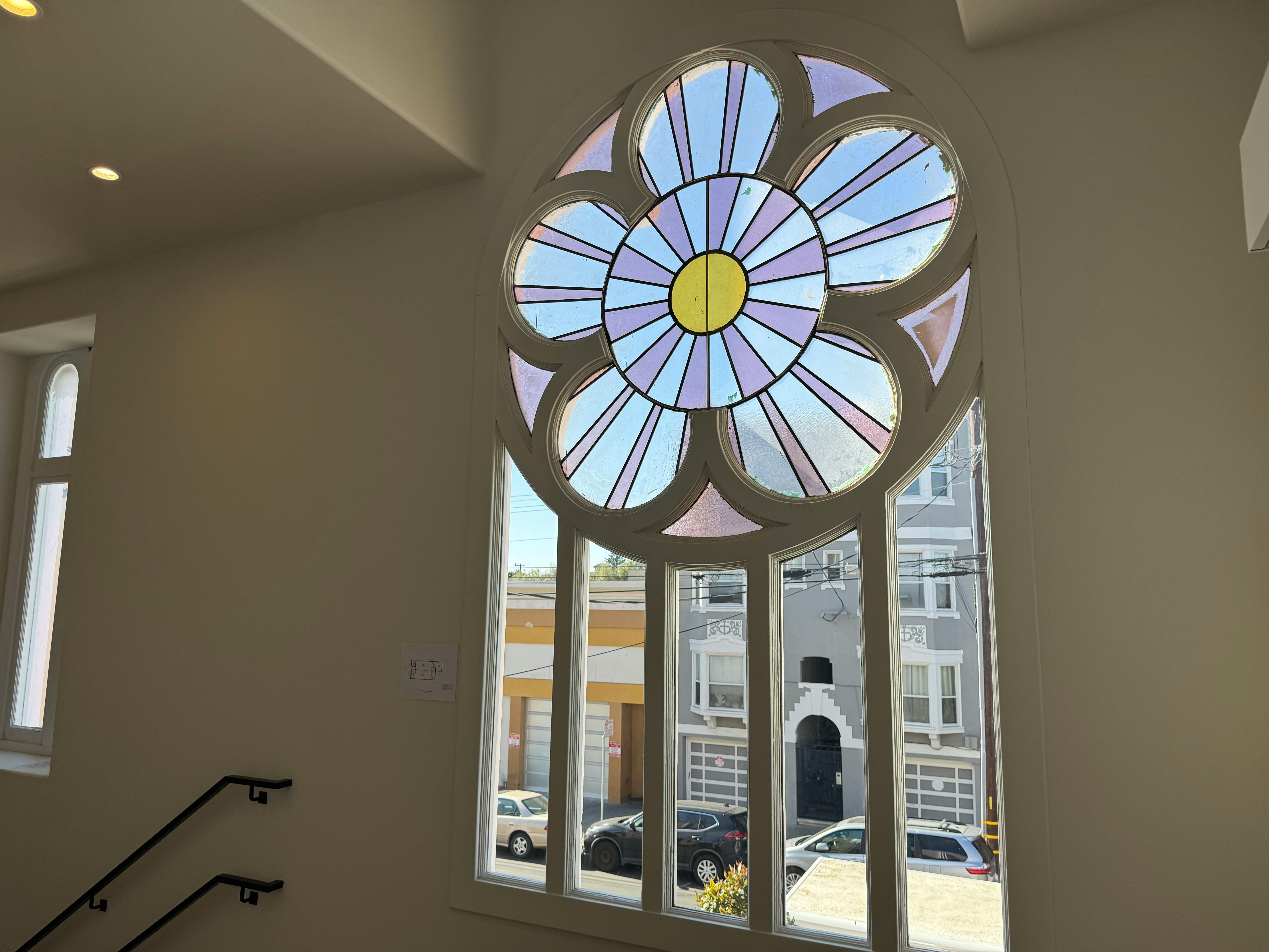 Stained glass window with a circular floral design above a large rectangular window