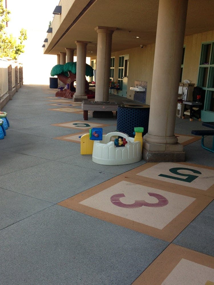 Outdoor walkway with pillars, play equipment, and numbered squares on the ground