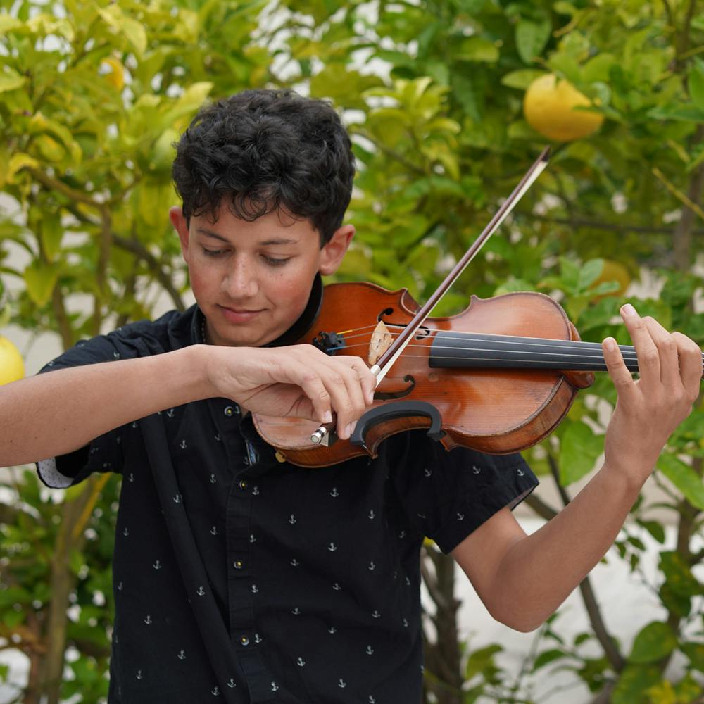 Child playing a violin outdoors