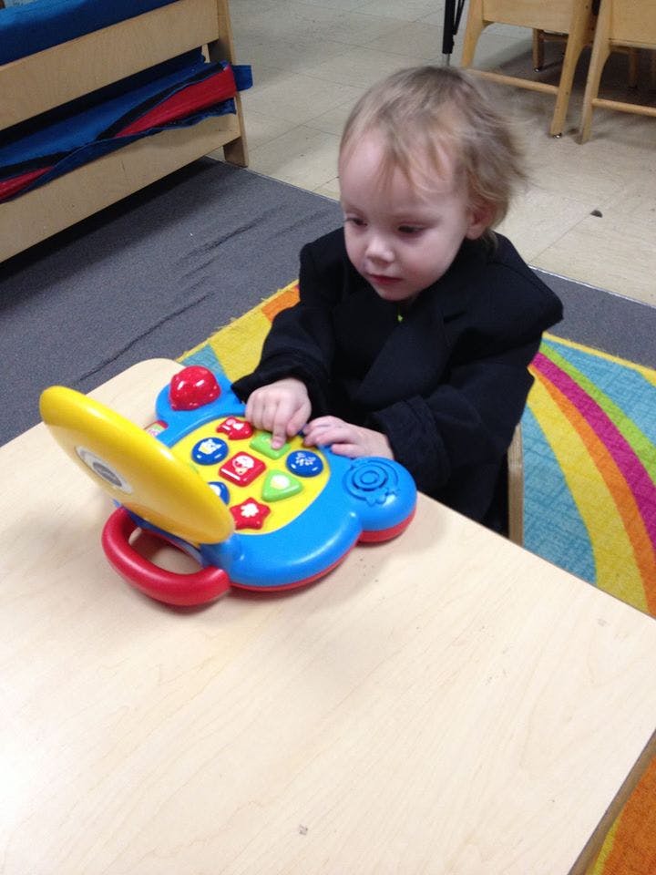 Child playing with a colorful toy phone on a table