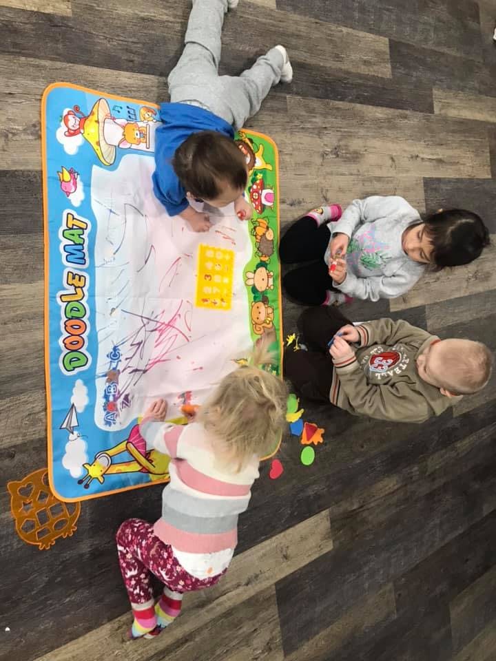 Four children playing on a doodle mat on the floor
