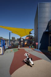 Playground with a yellow shade sail and ride-on toys