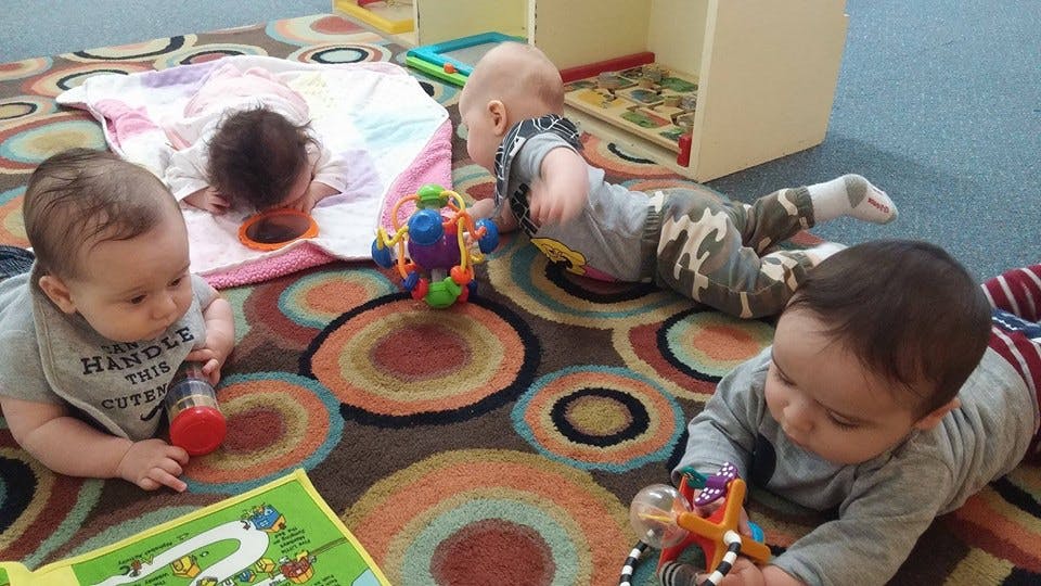 Multiple babies playing on a colorful rug