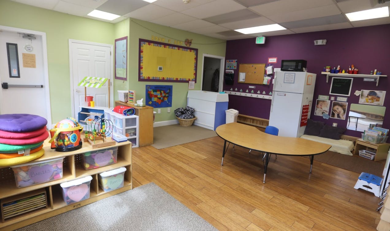 Classroom with light green and purple walls, wooden floor, and small tables