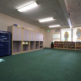 Empty classroom with green carpet and storage units