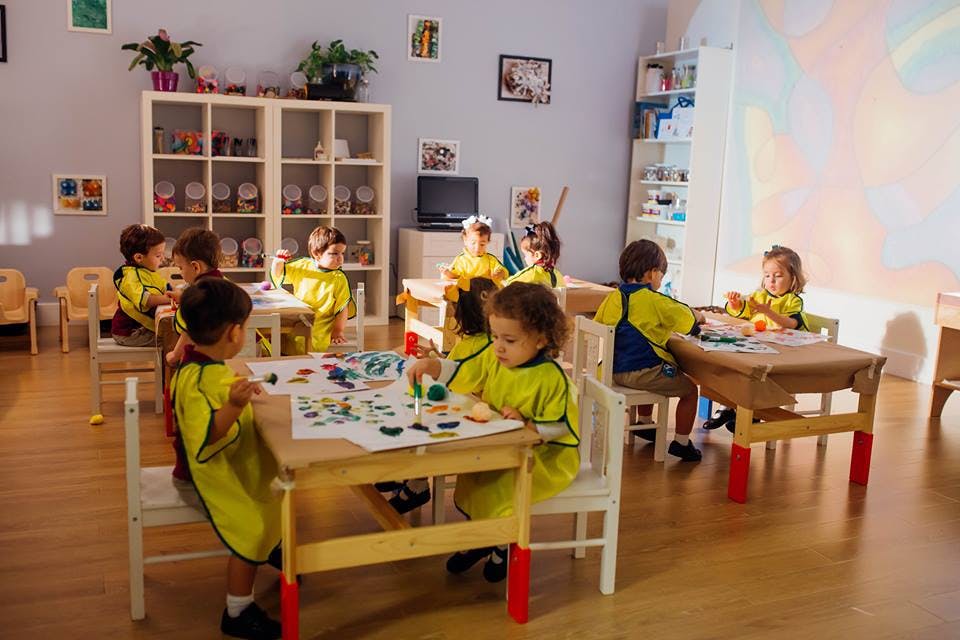 Children in yellow shirts sitting at tables in a classroom