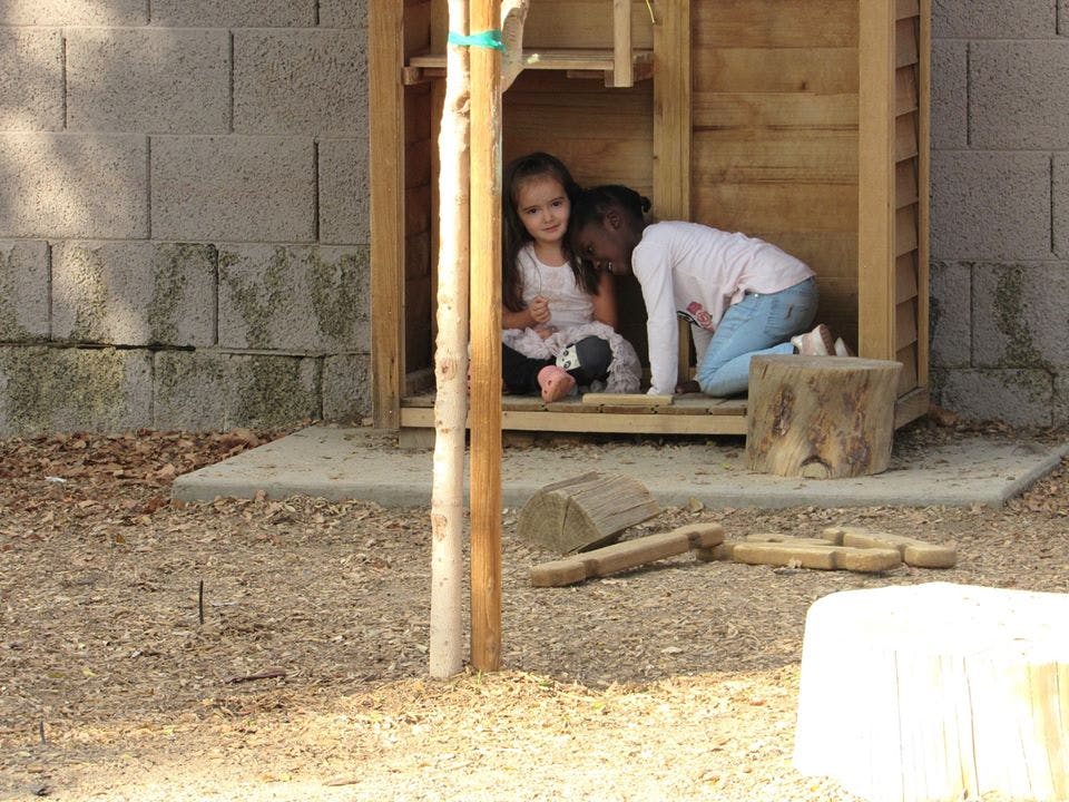 Two children playing inside a small wooden structure