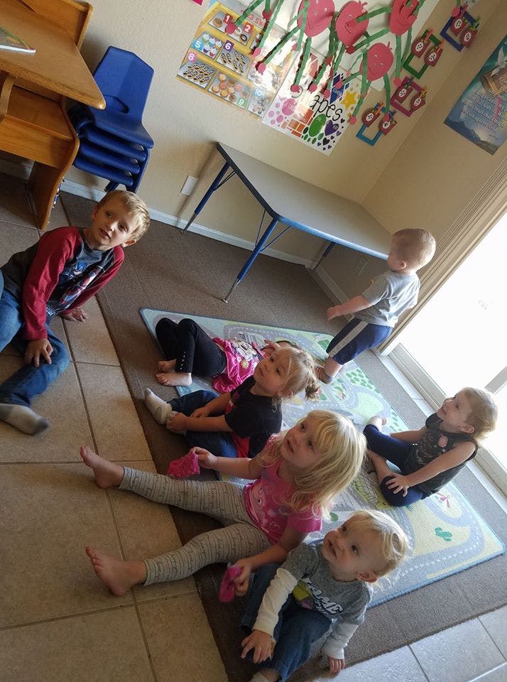 Multiple children sitting and lying on the floor in a room