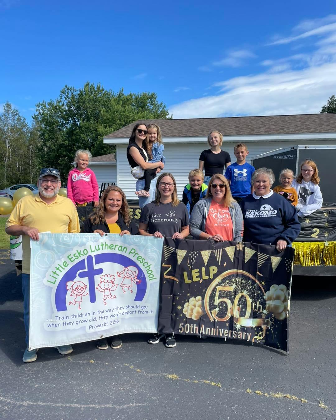 People and children holding two banners that read "Little Esko Lutheran Preschool" and "LELP 50th Anniversary"