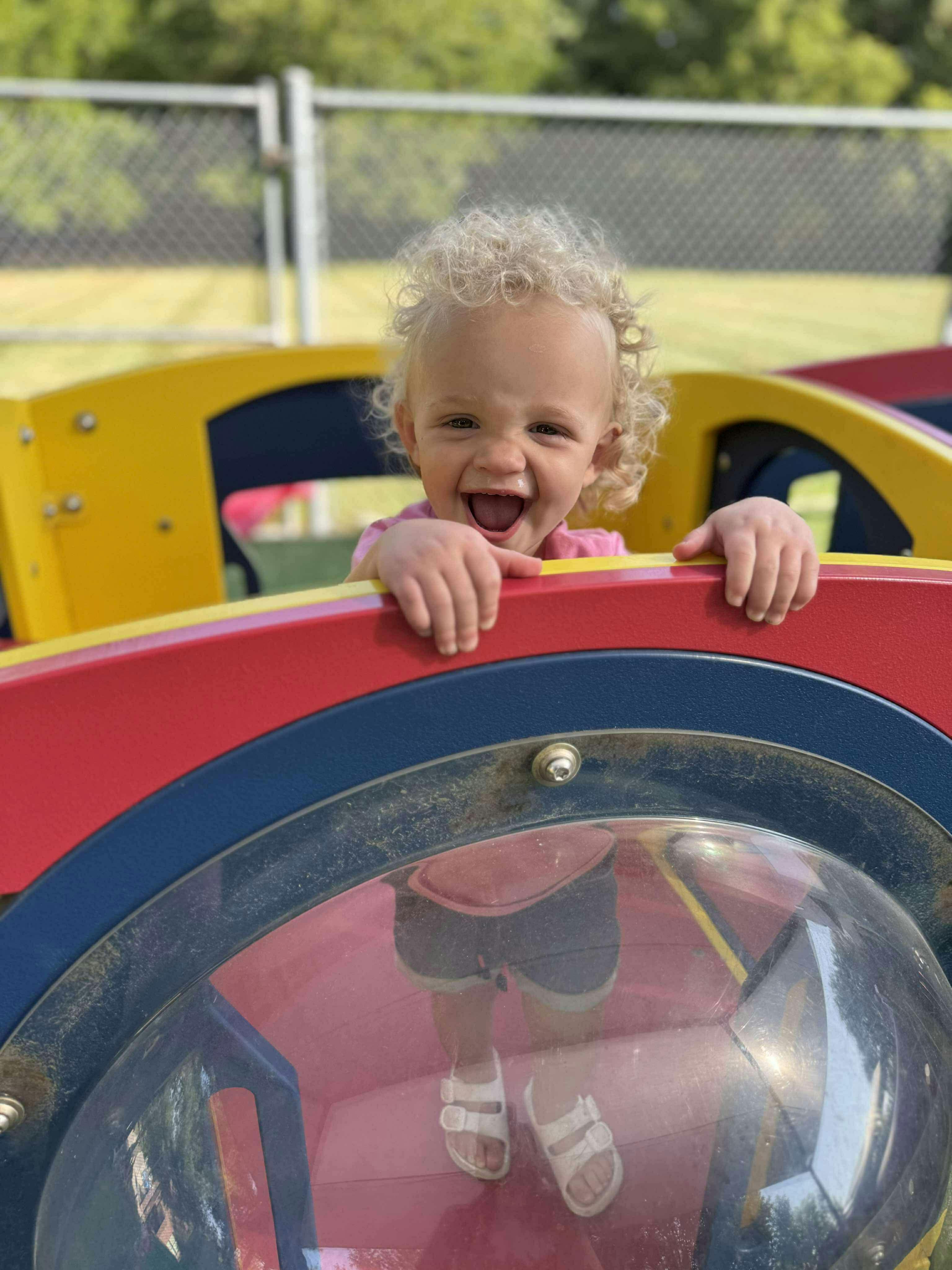 Child smiling while looking over a colorful playground structure