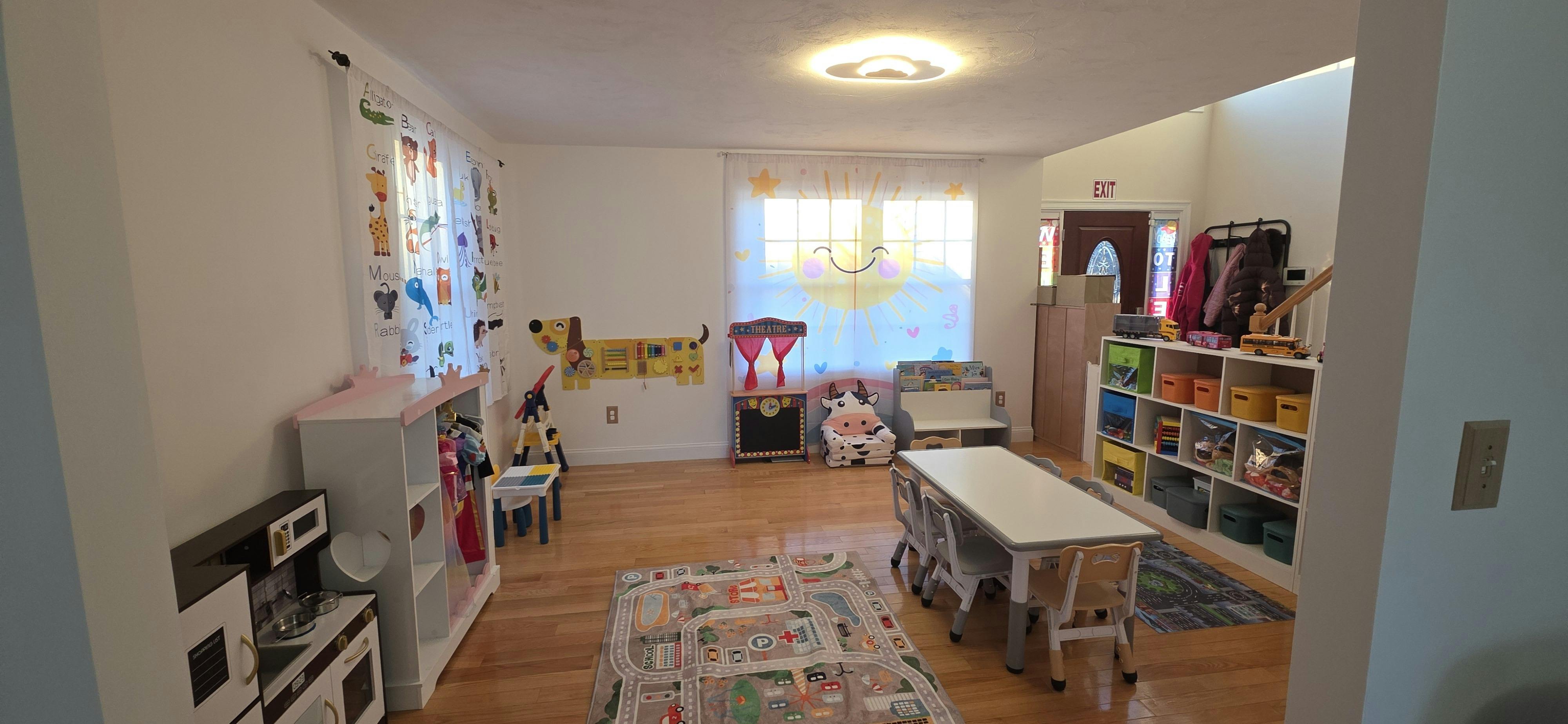 A classroom with small tables and chairs, play kitchen, and toy shelf