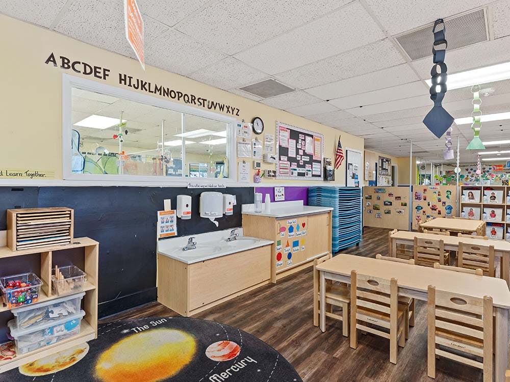An empty classroom with child-sized tables and chairs