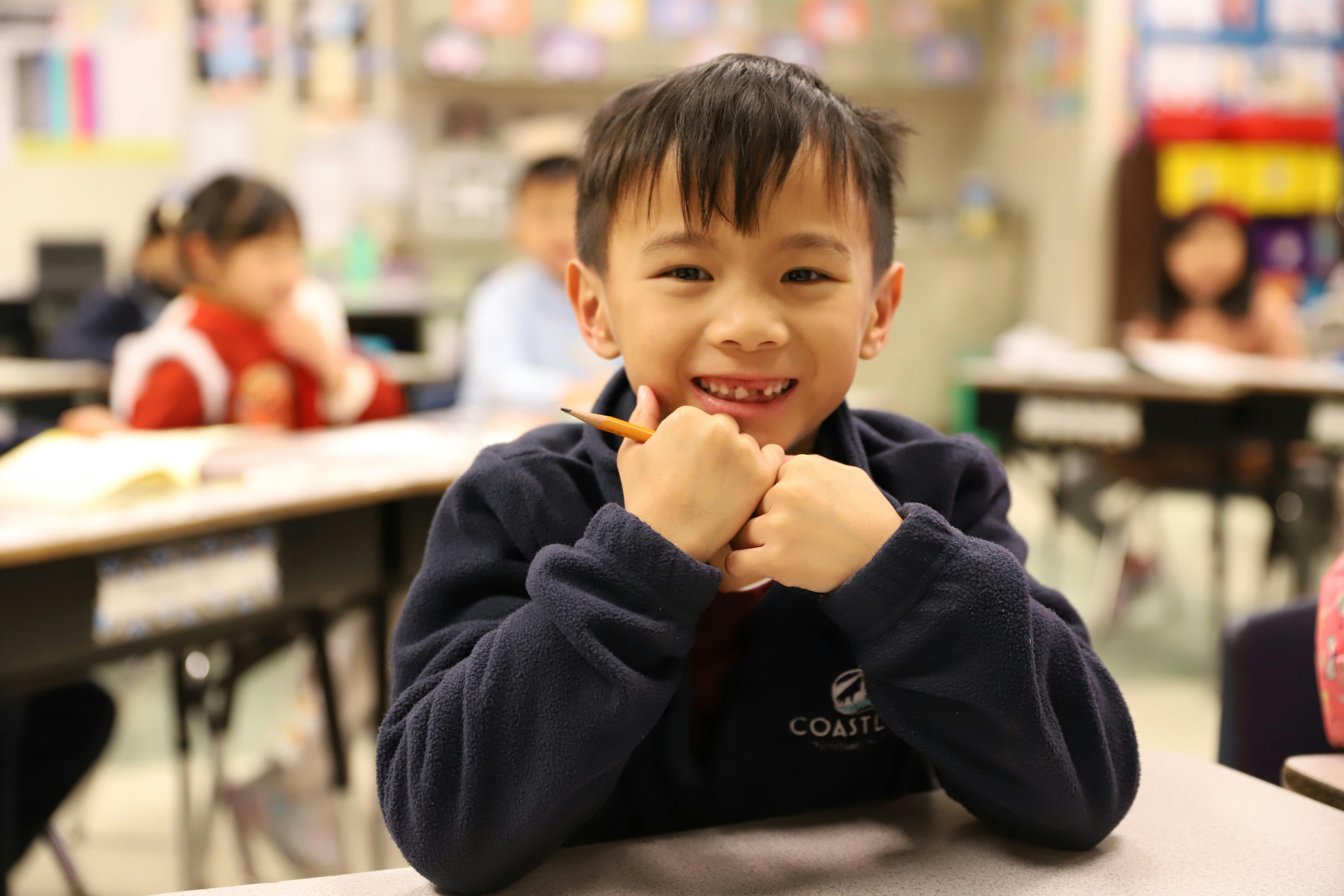 Child in a classroom holding a pencil