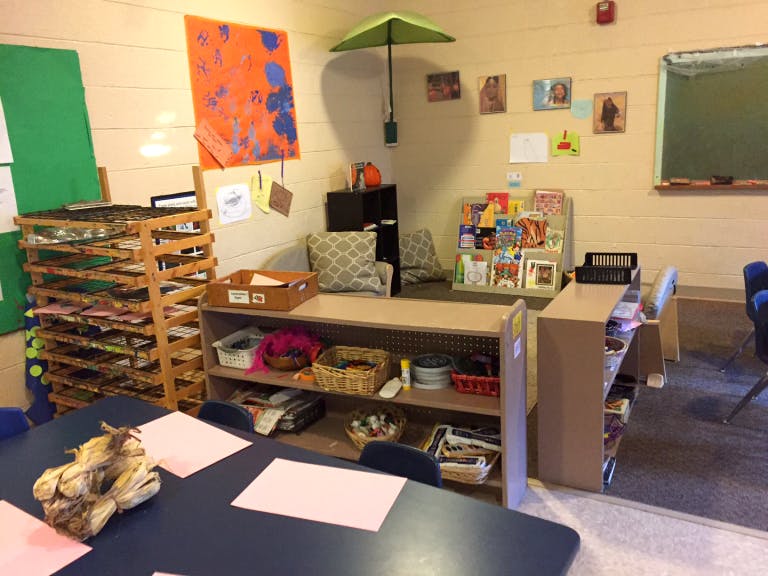 Classroom with tables, shelves, and artwork on the walls