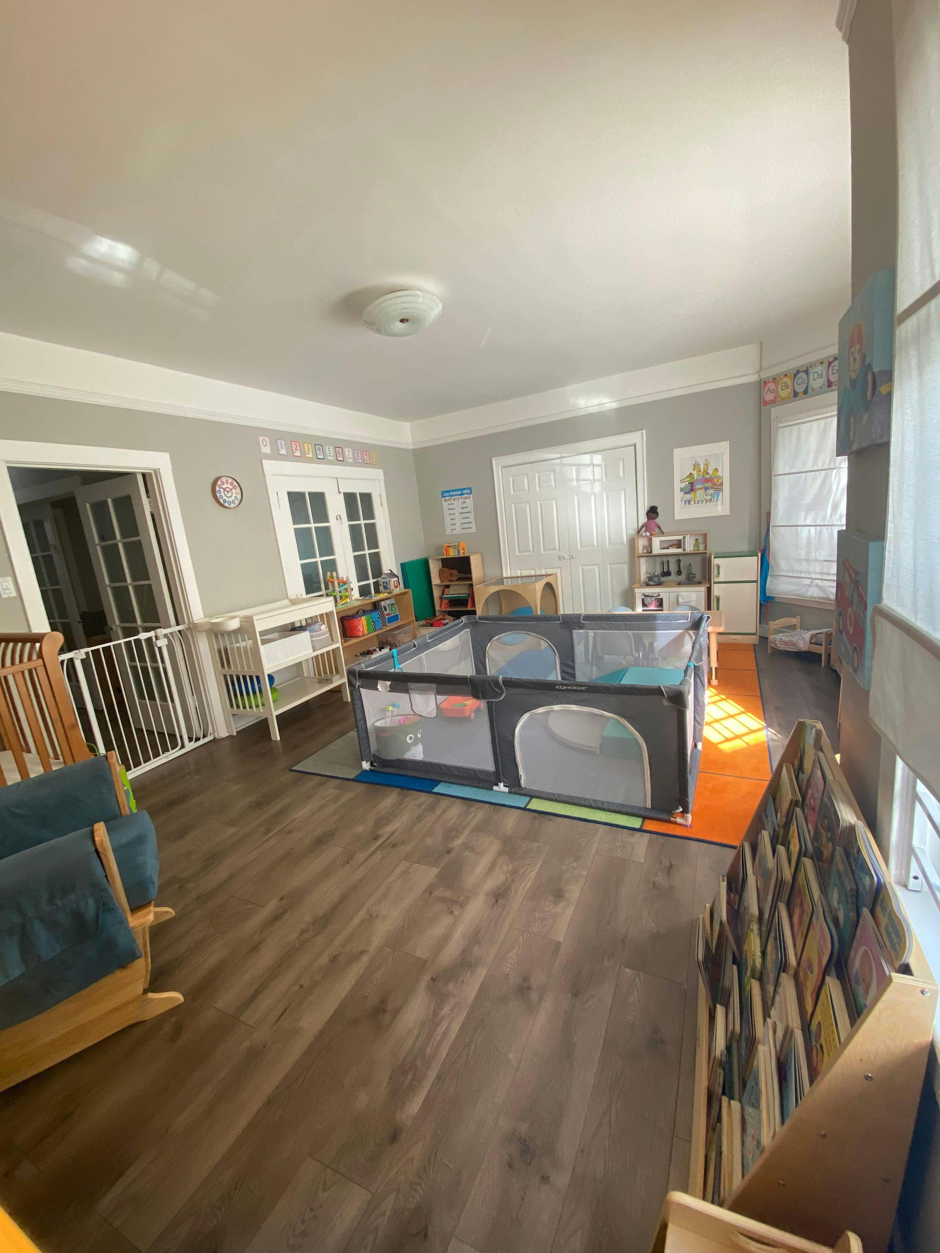 Playroom with a large playpen, crib, and rocking chair