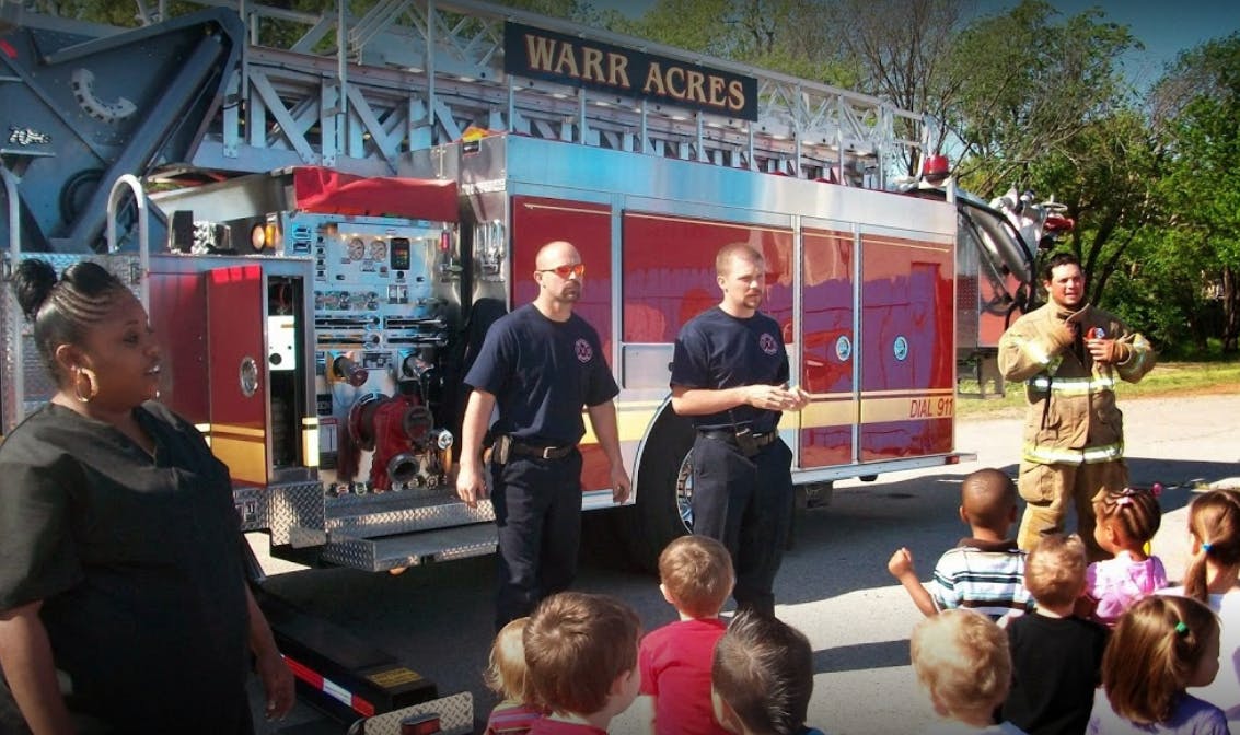 Firefighters talking to children in front of a fire truck