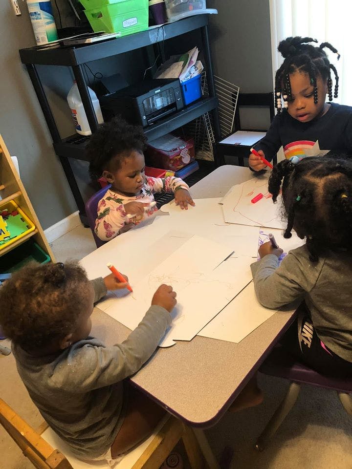 Four children drawing at a table