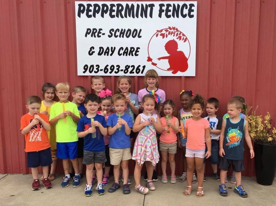 Group of children standing in front of a sign for Peppermint Fence Pre-School & Day Care