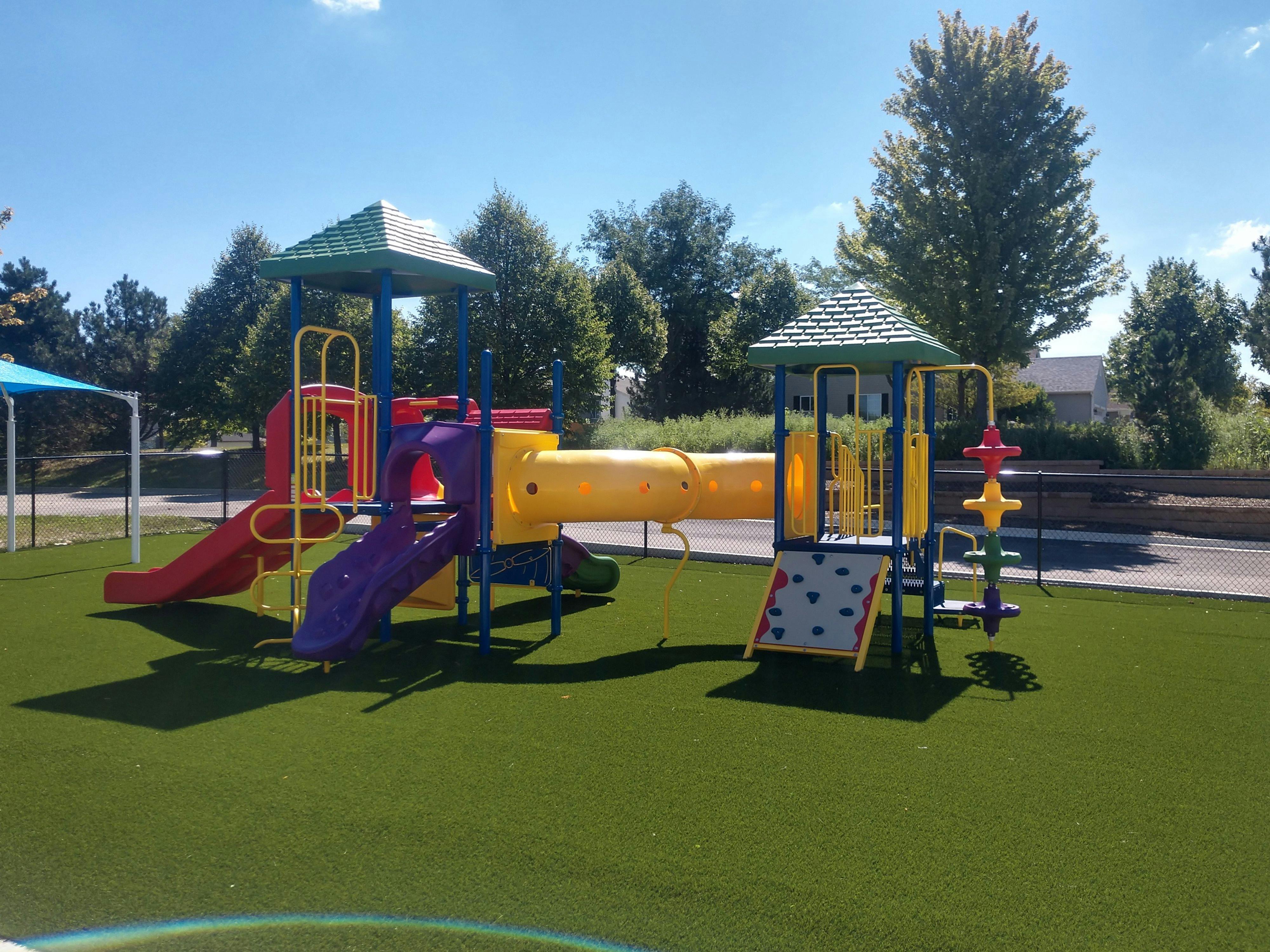 Colorful playground structure on artificial green turf on a sunny day