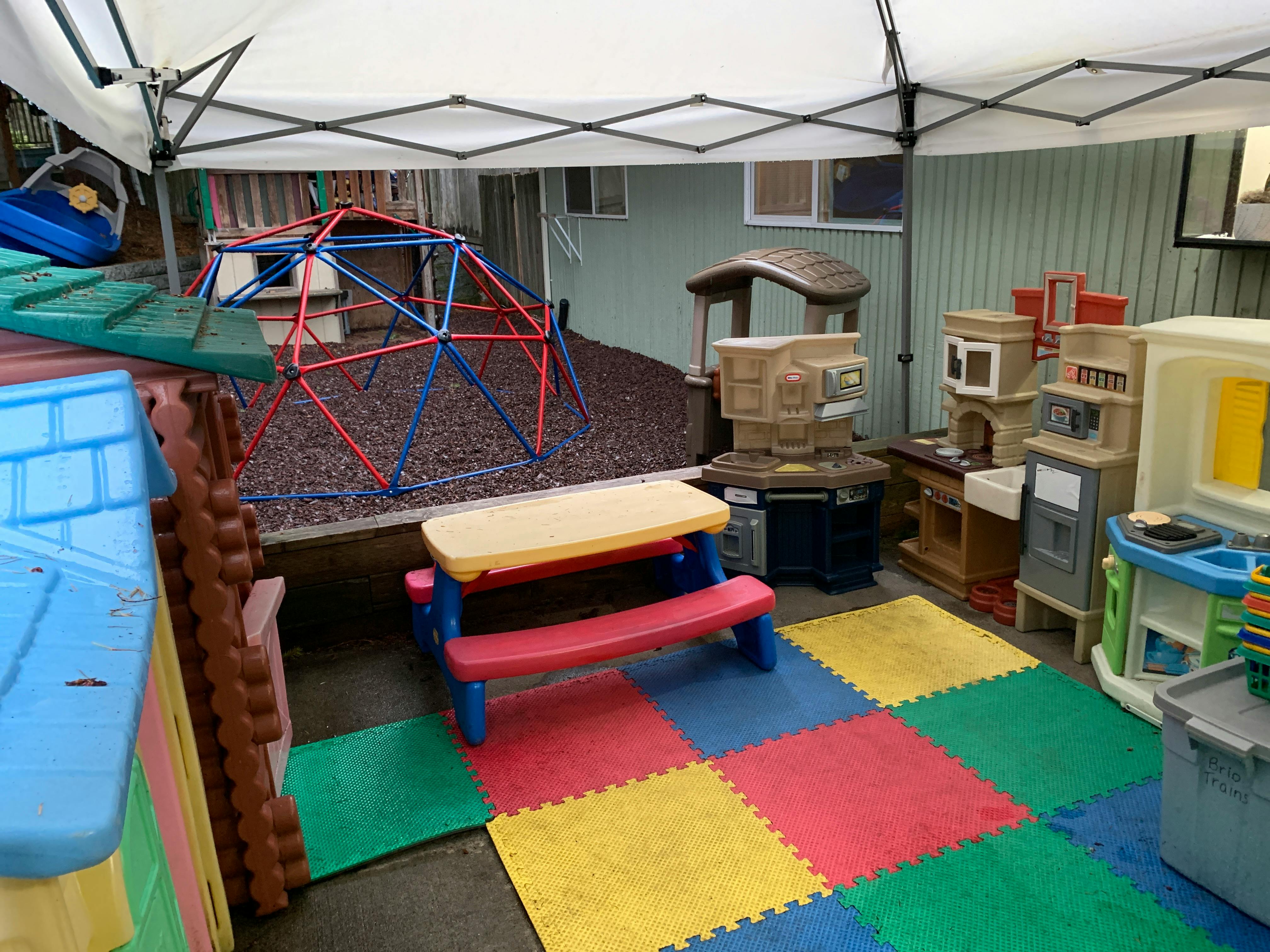 Outdoor play area with a climbing dome, play kitchen, and picnic table