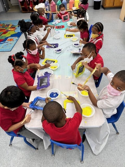 Children painting at a table in a classroom