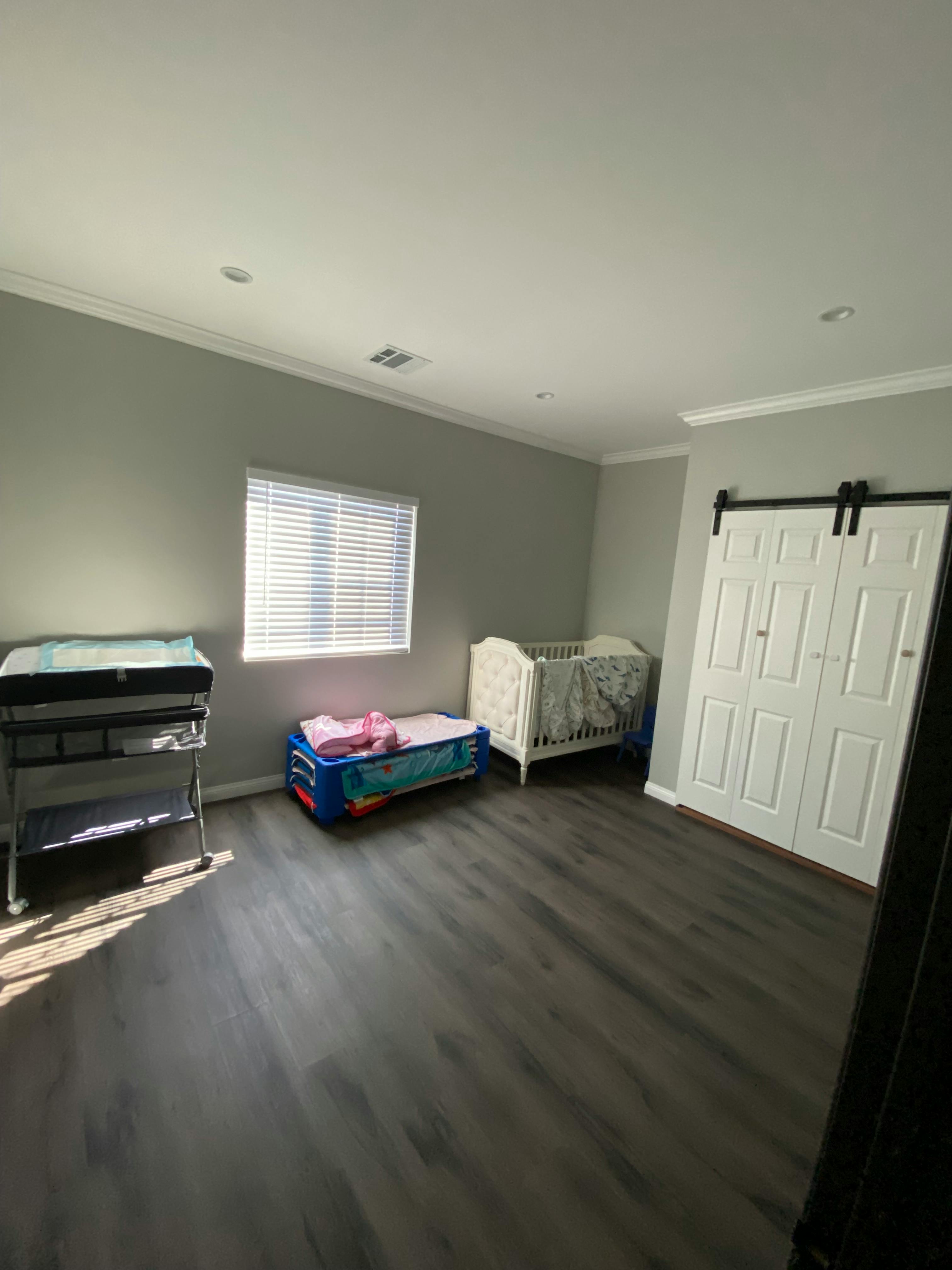 Nursery room with a changing table, playpen, and crib