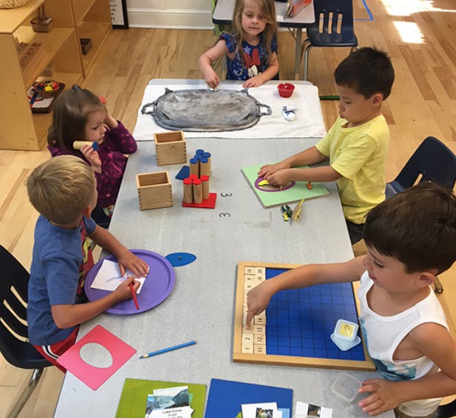 Children working on various activities at a table in a classroom