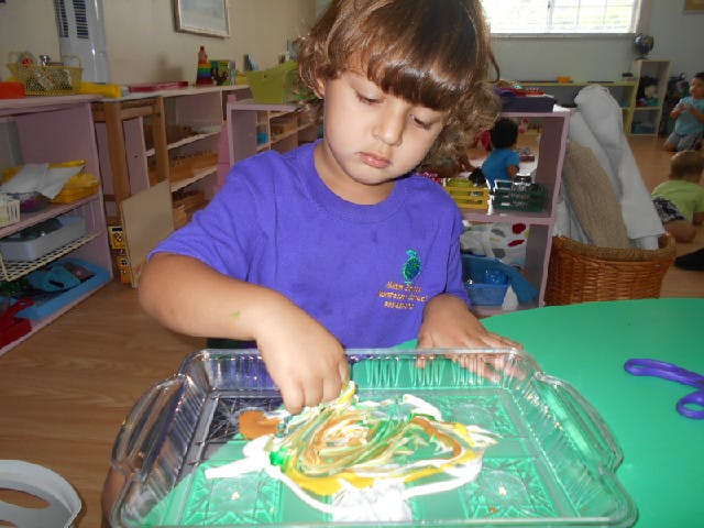 Child mixing paint in a clear tray