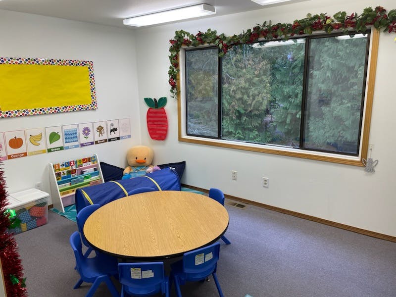 Classroom with a round table and chairs, play tunnel, and large window