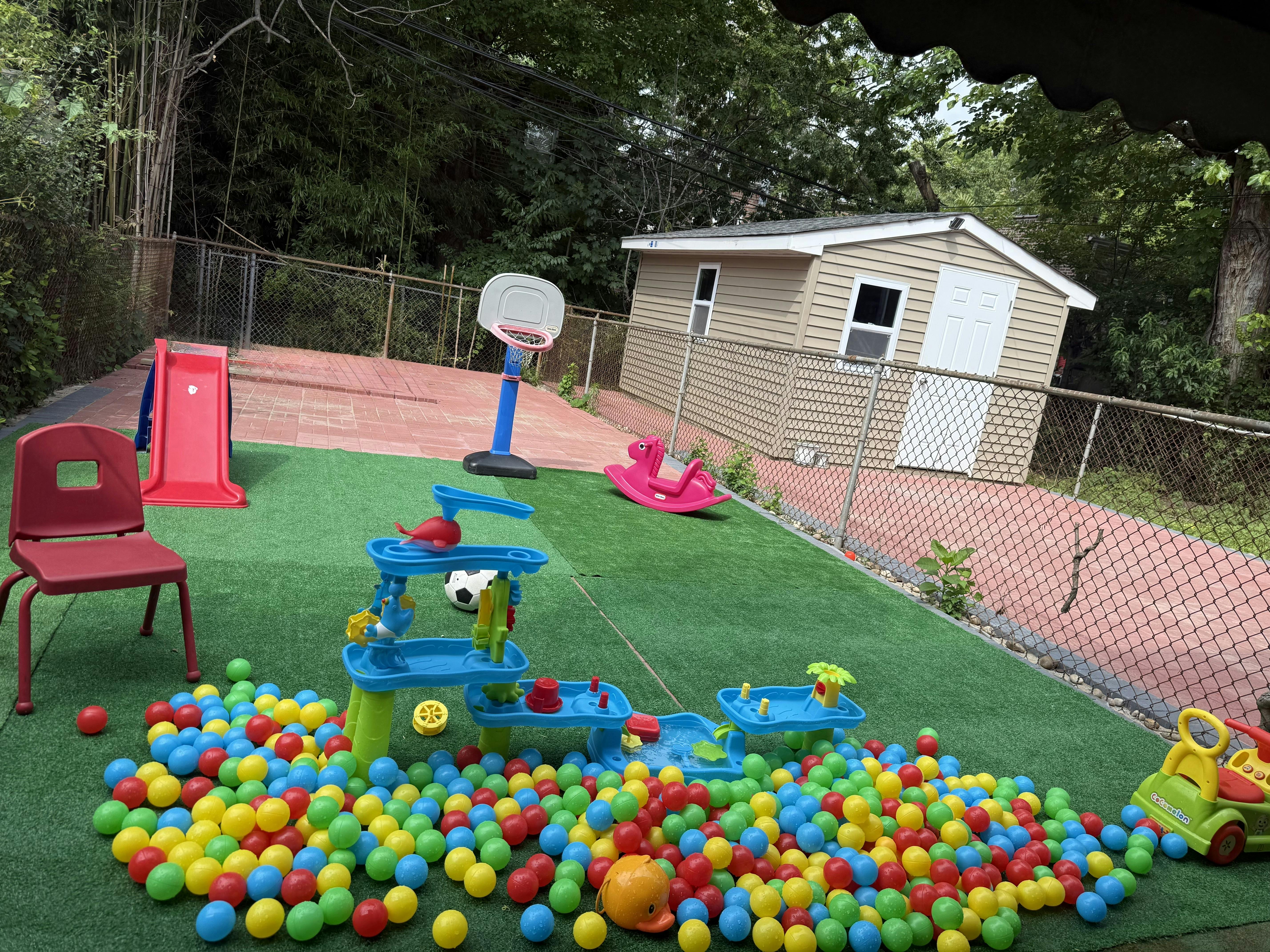 Outdoor play area with ball pit, water table, slide, and basketball hoop