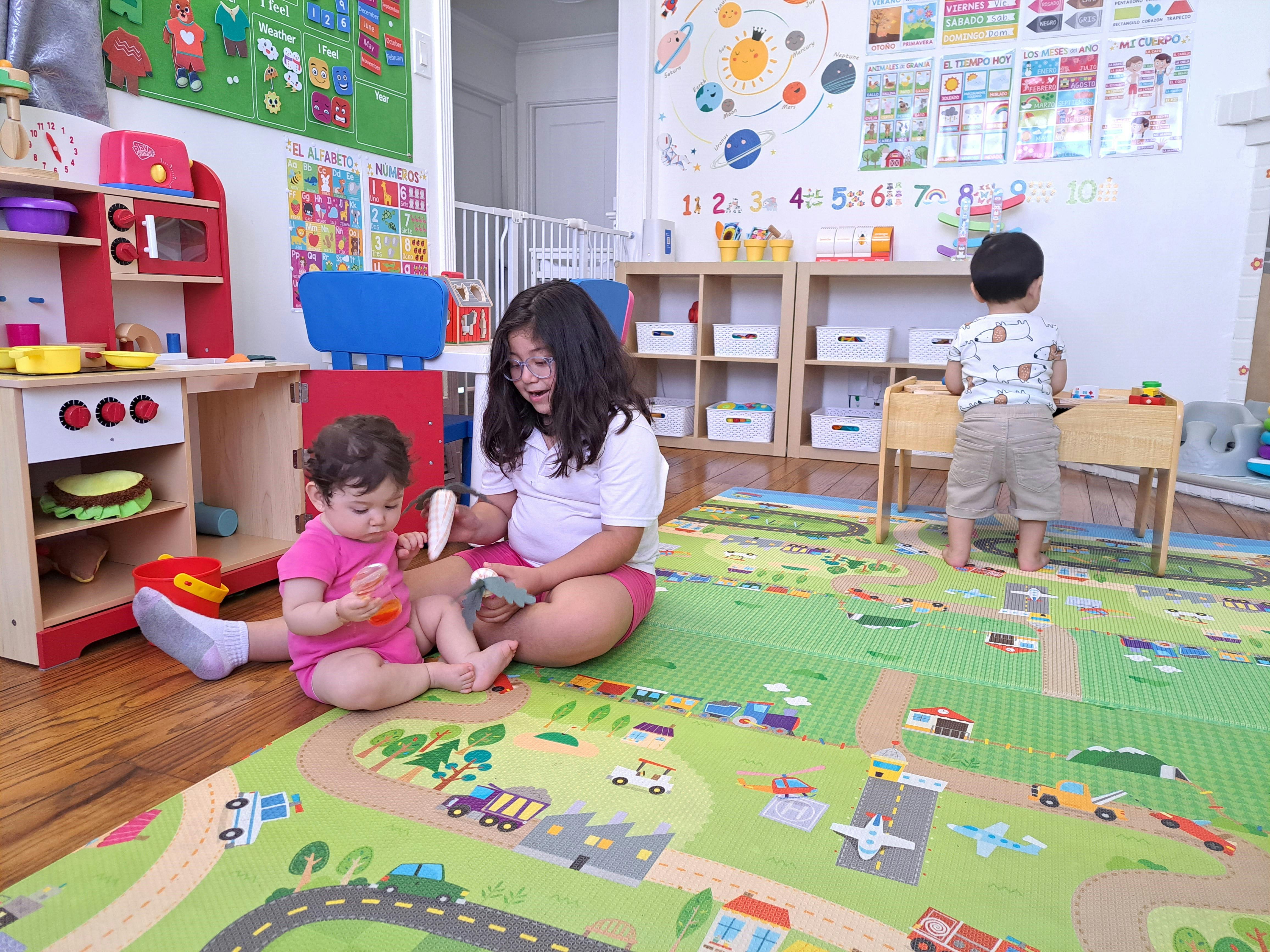 Two children playing on a mat in a classroom, one teen and one child