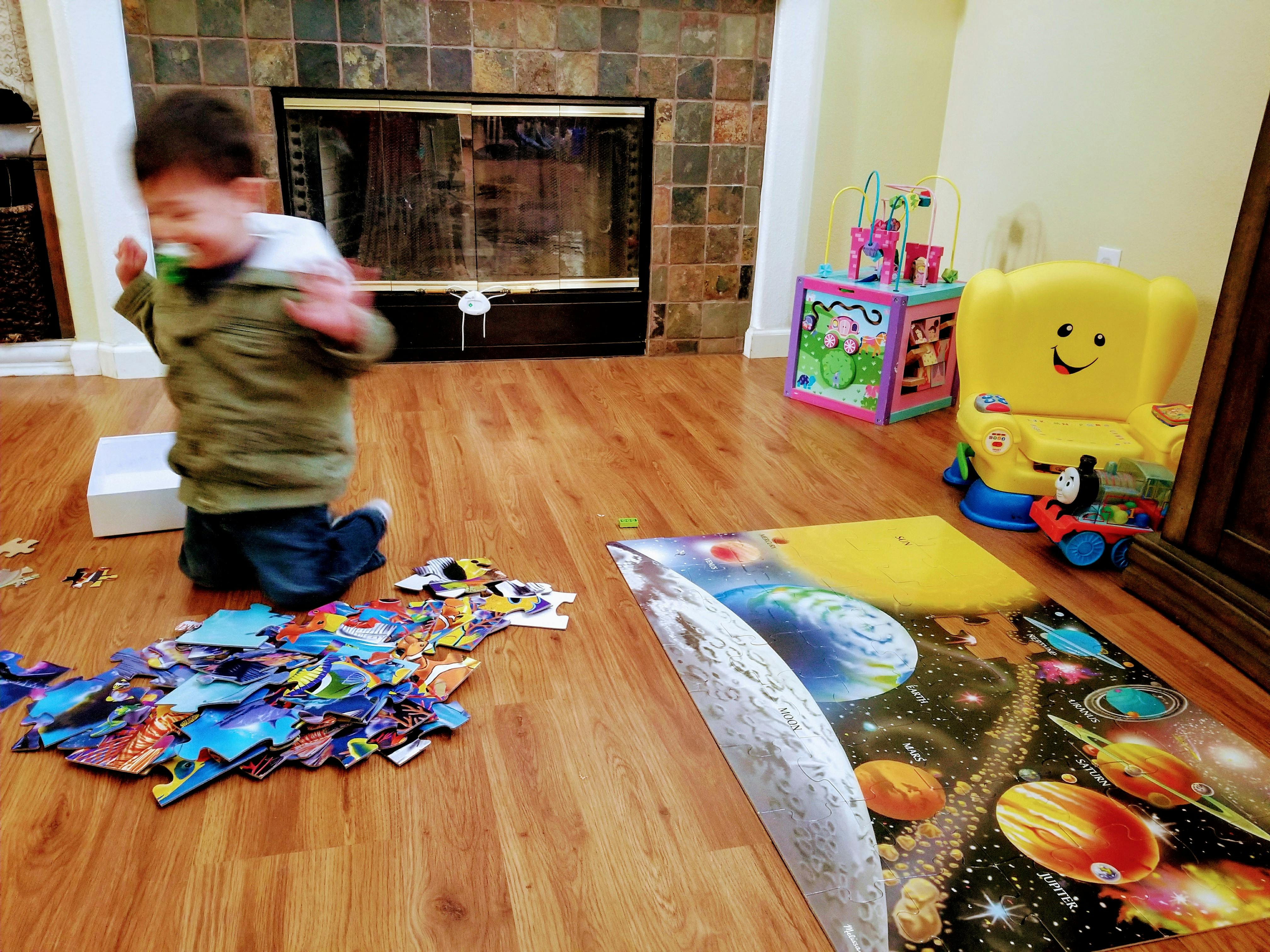 Child kneeling on floor next to scattered puzzle pieces