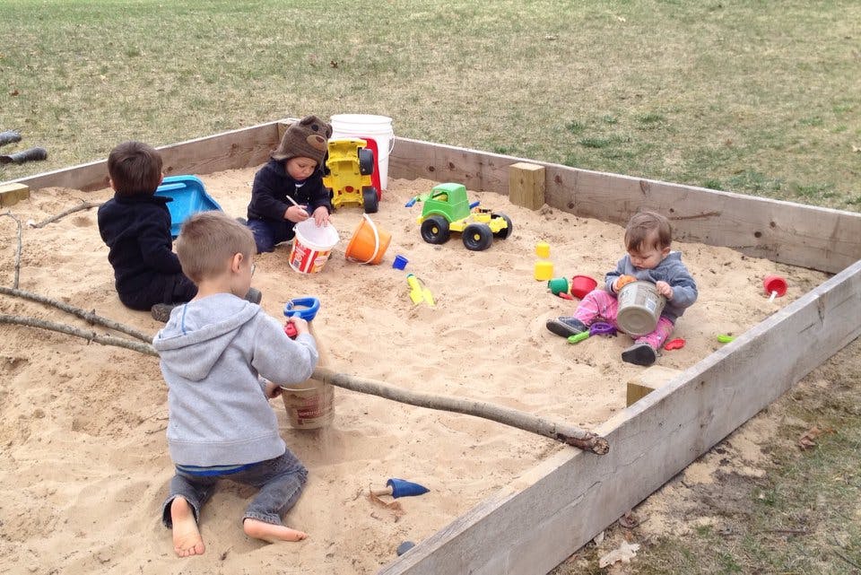 Children playing in a sandbox with toys