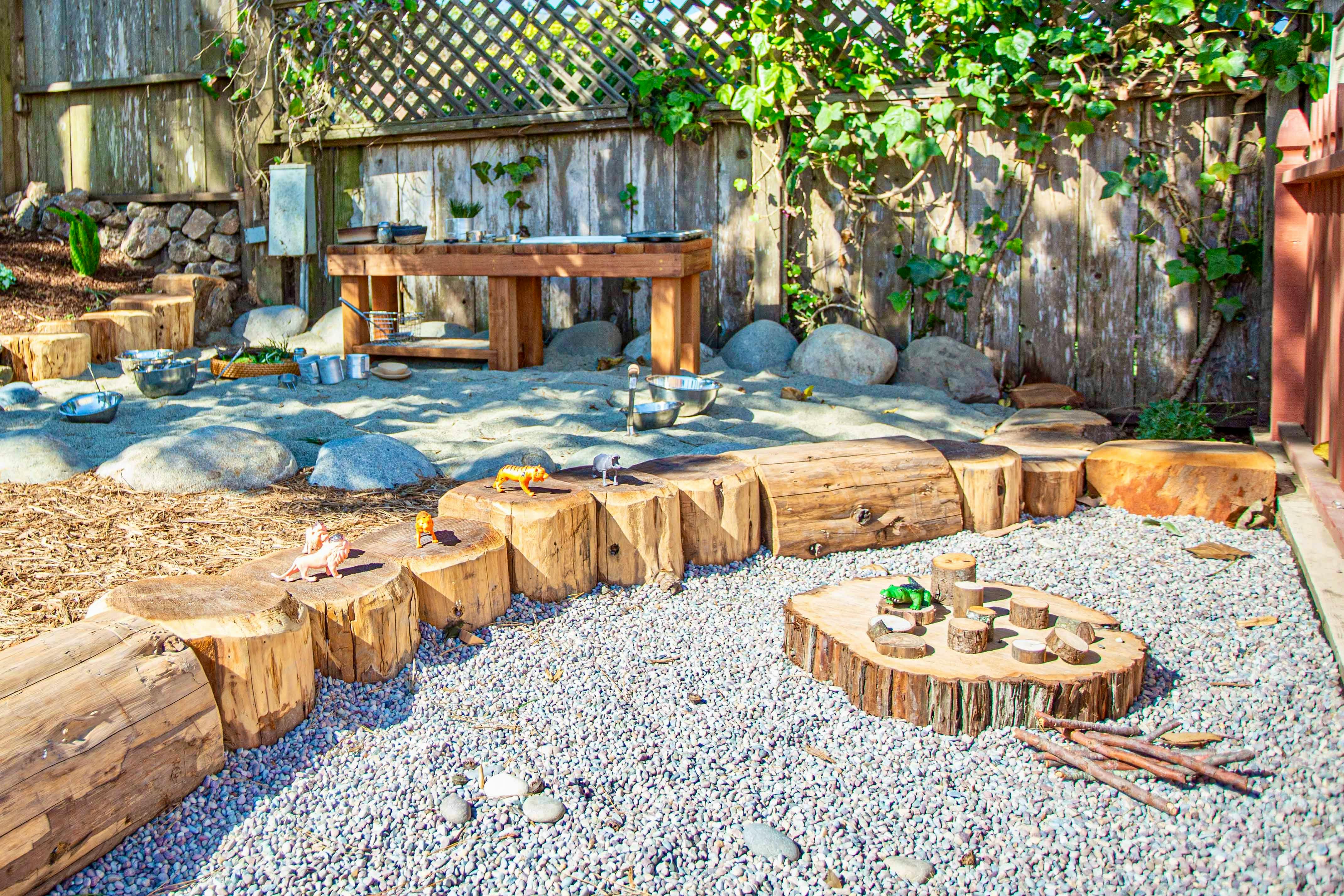 Outdoor play area with tree stumps and gravel