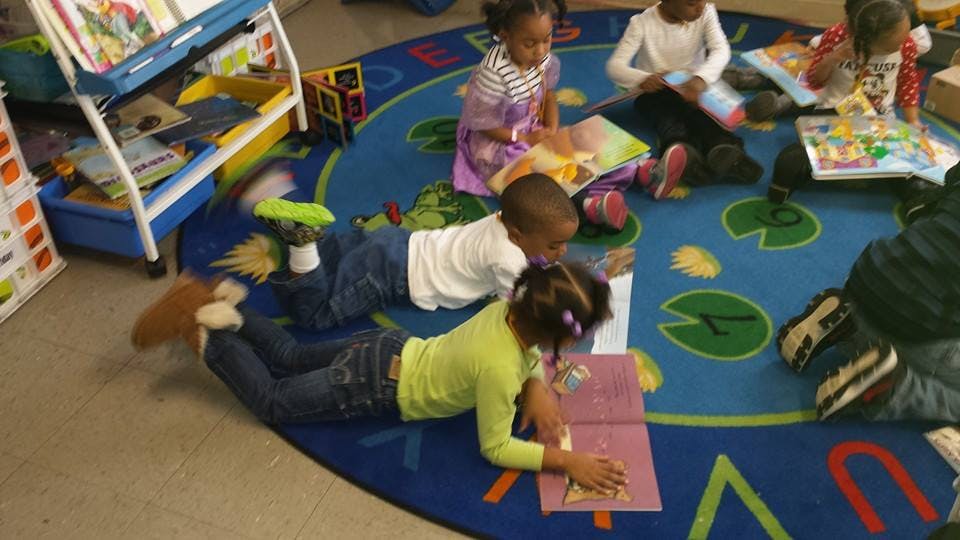 Children reading books on a rug in a classroom