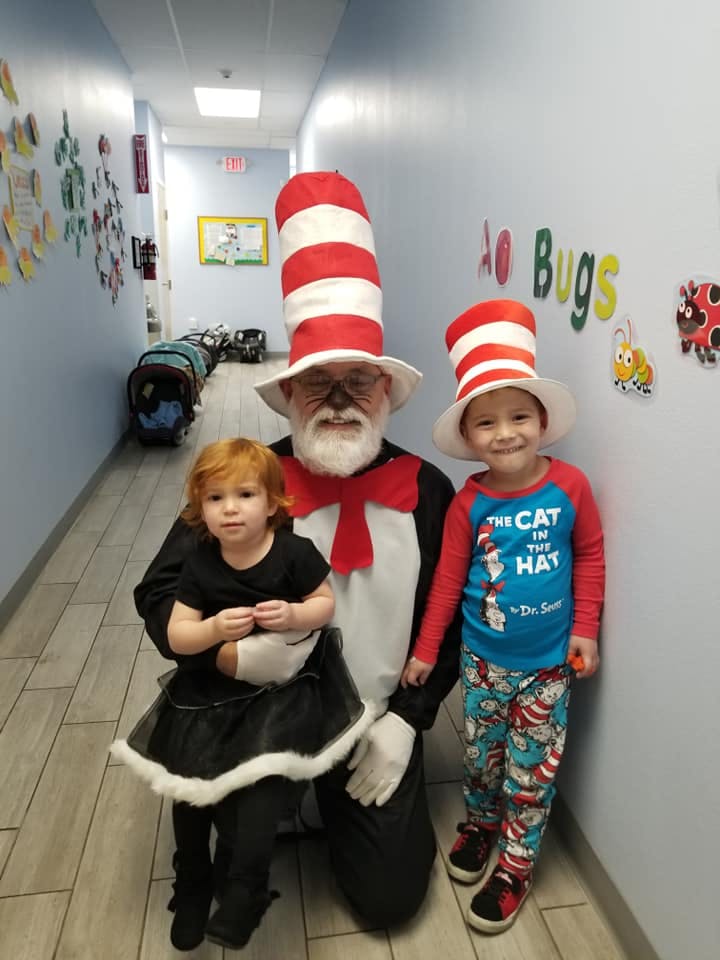 Person dressed as Cat in the Hat with two children in a hallway