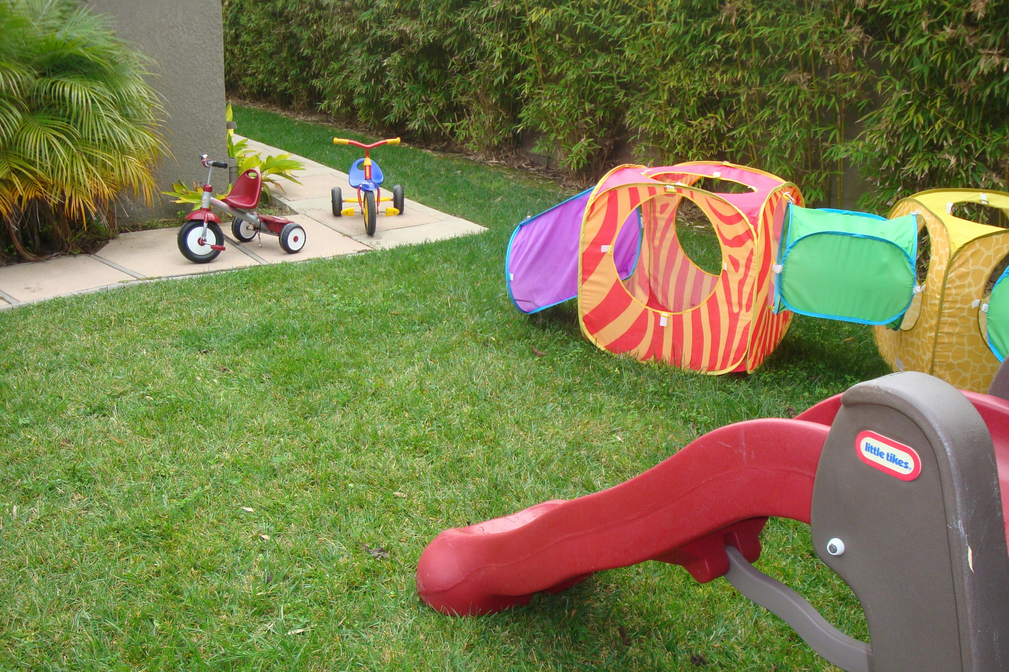 Childrens outdoor play equipment including tricycles, pop-up tents and a slide