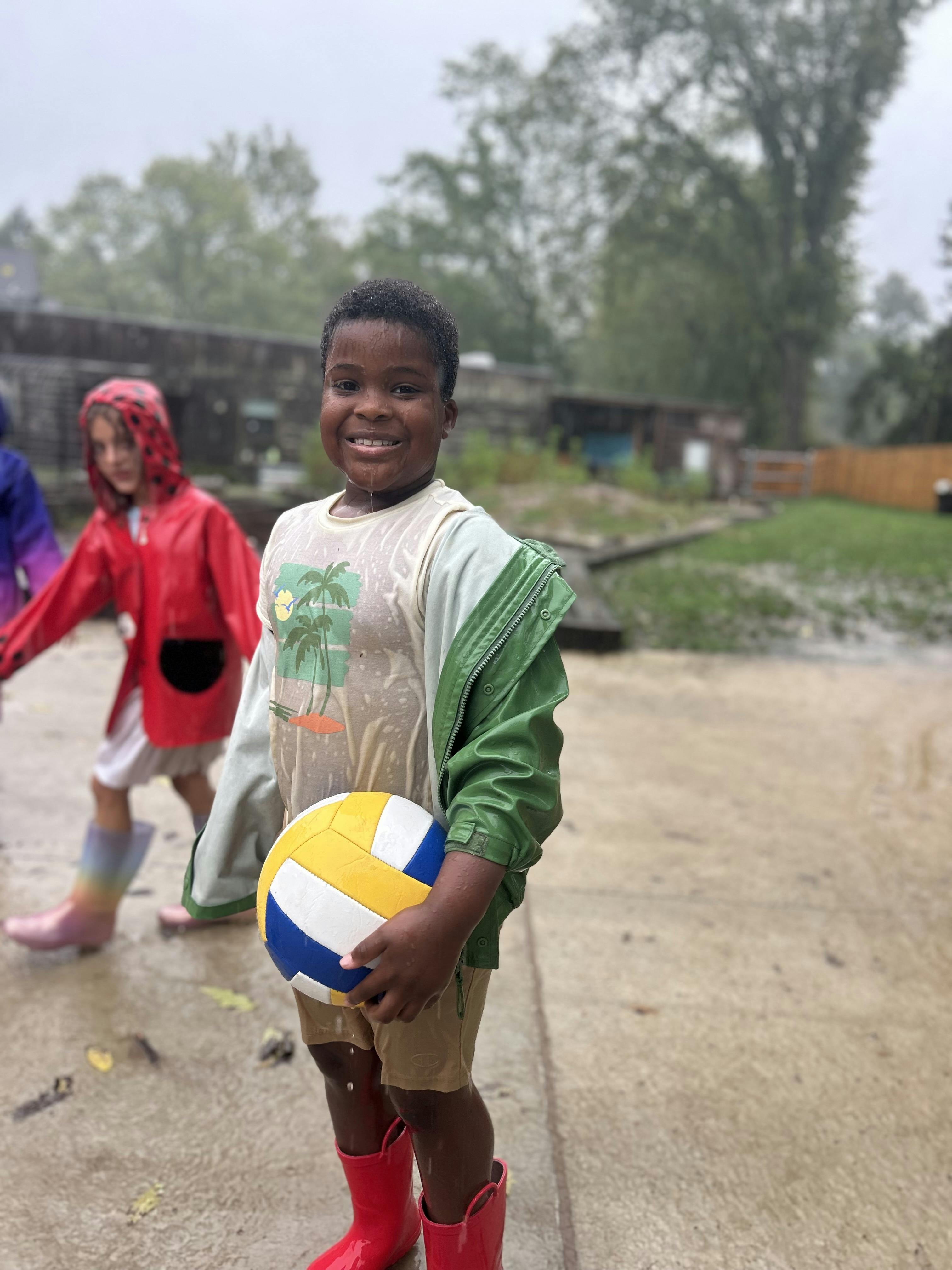 Child holding a volleyball in the rain