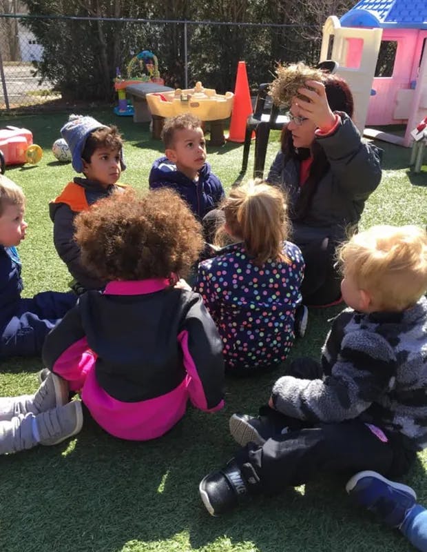 Adult and children sitting on grass in a circle