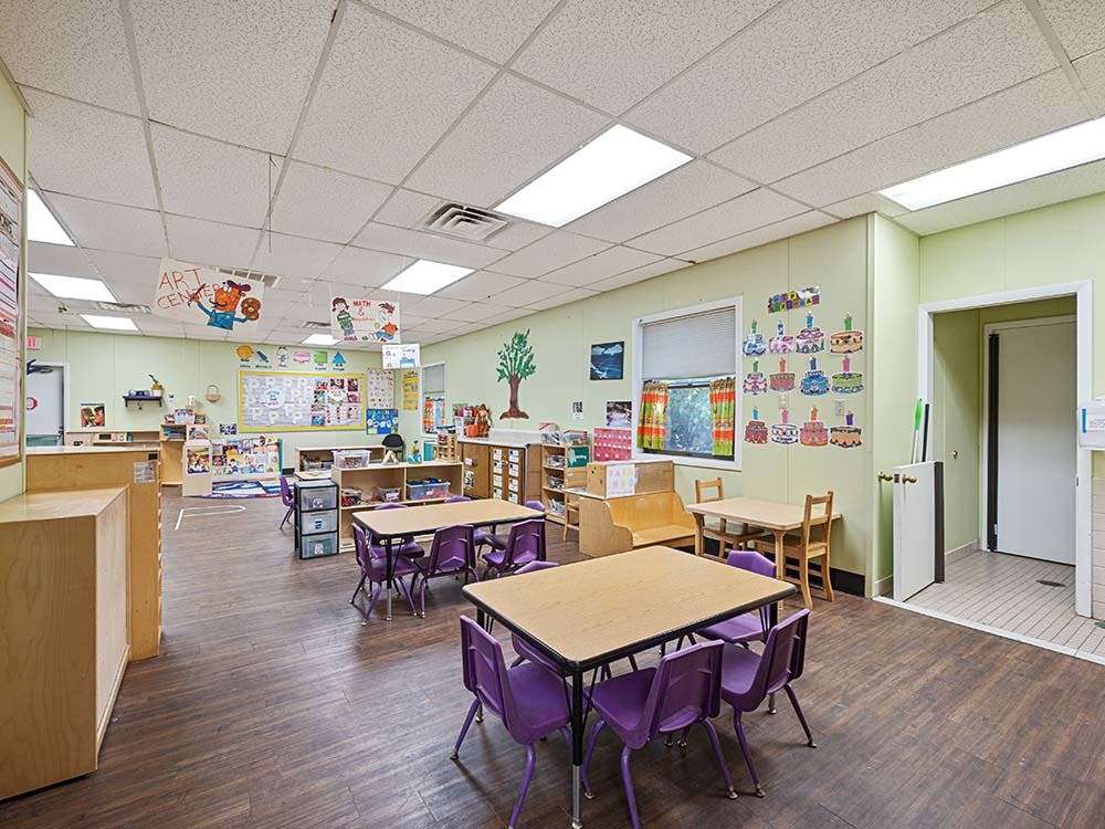 Classroom with small tables and chairs, decorated with children's artwork