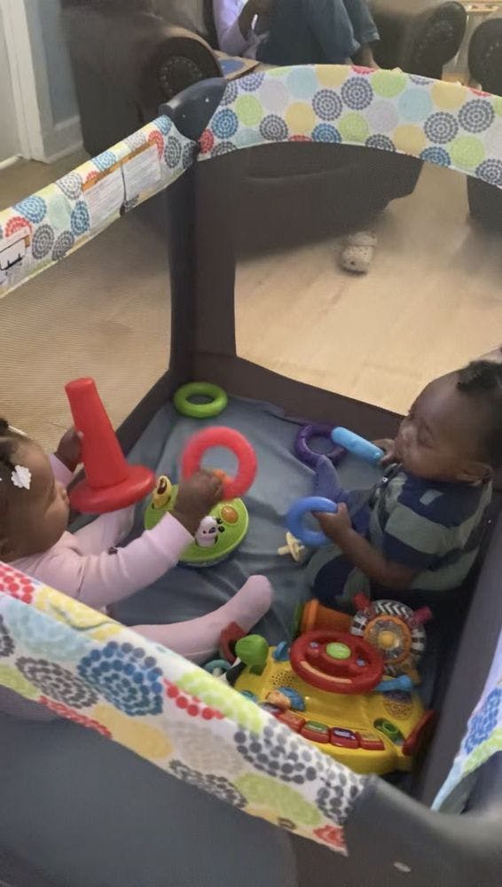 Two children playing with toys in a playpen