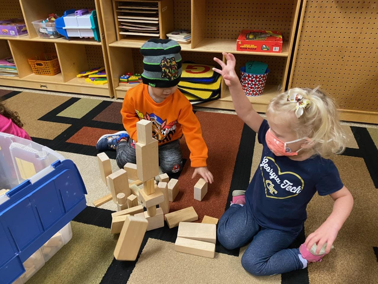 Two children playing with wooden blocks on the floor