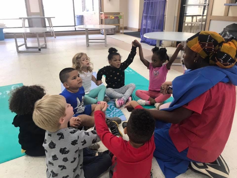 Adult and children sitting in a circle holding hands